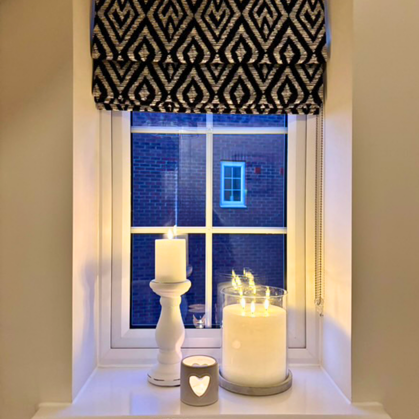 Window with patterned curtain, candles on a windowsill, showing ways to style a Large stone-base hurricane candle holder