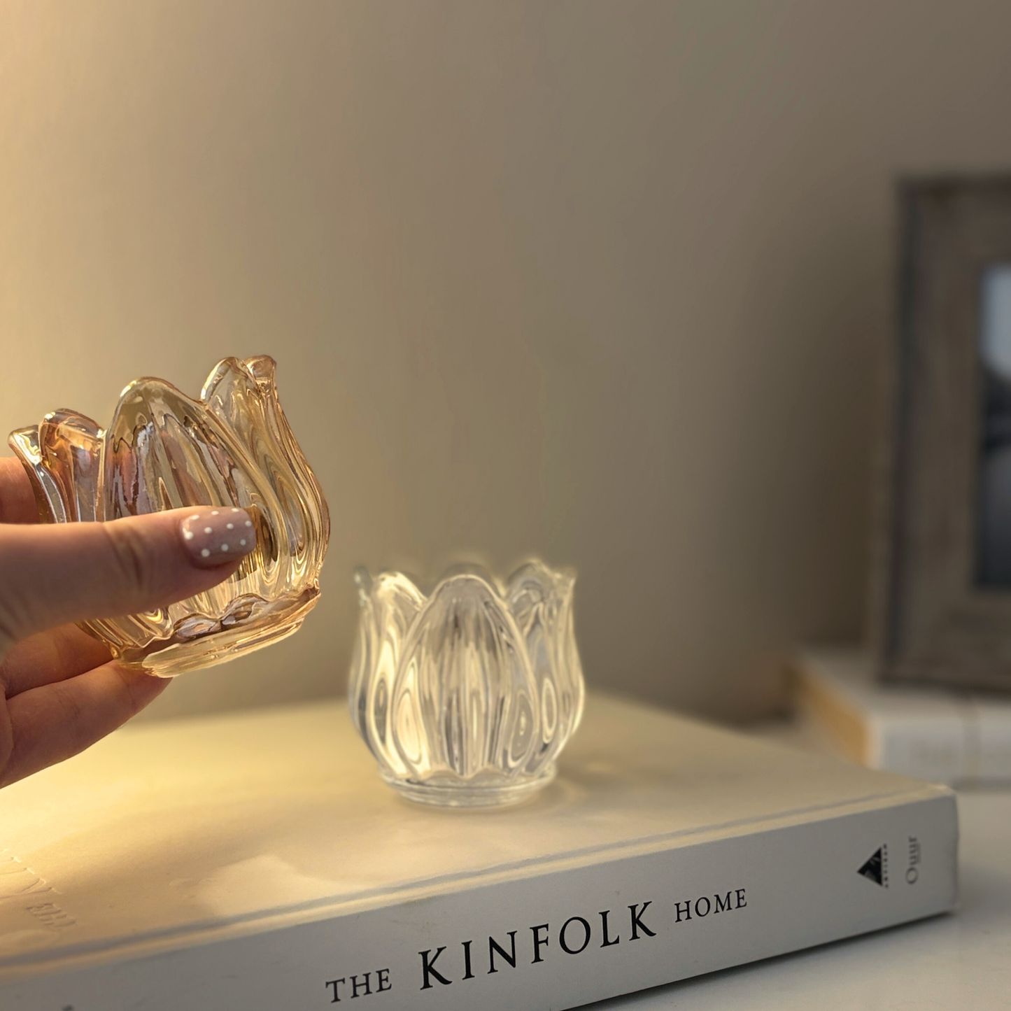 Hand holding a glass decorative item on a book titled 'The Kinfolk Home'.