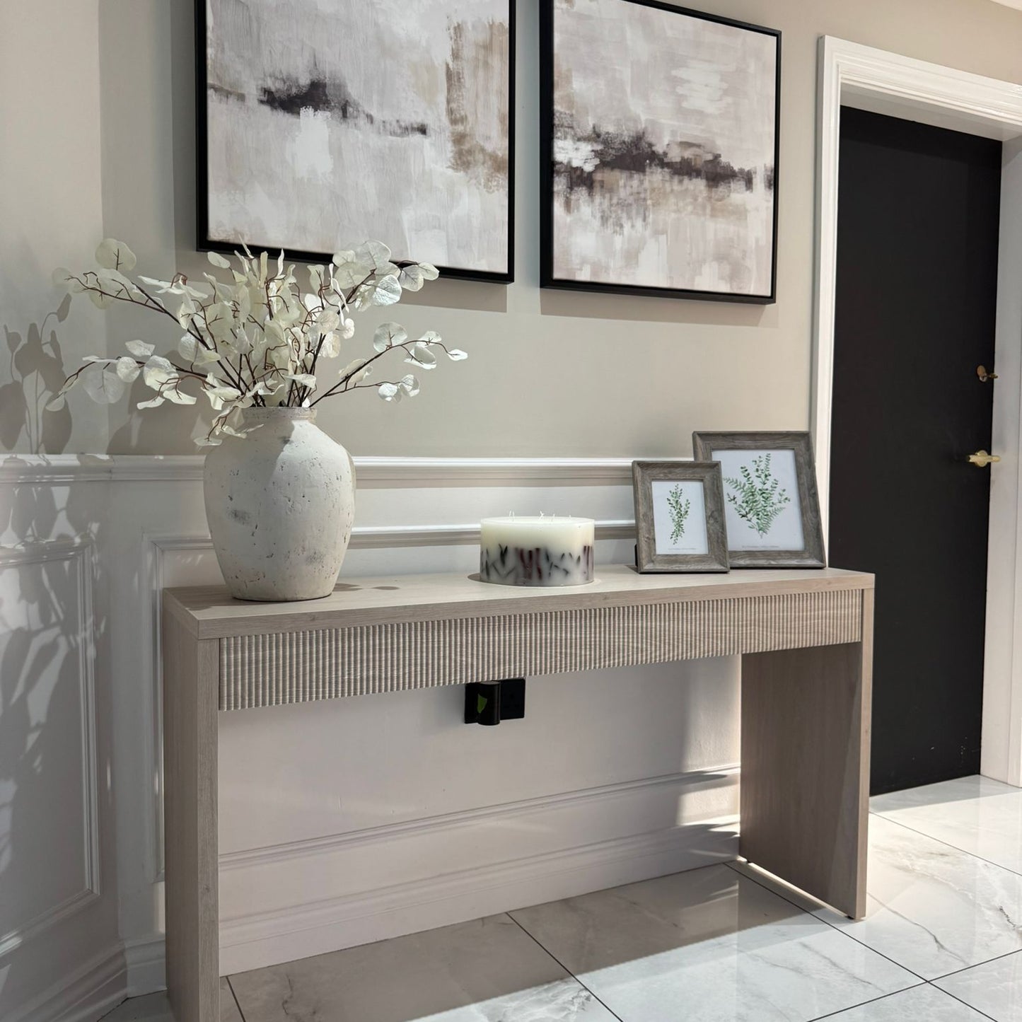 Modern interior with a console table, decorative items, and abstract art on the wall.